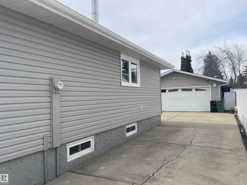 The property features grey siding, white-trimmed windows, and a detached garage with a white overhead door - 14212 30 Street, Edmonton, AB - Outdoor With Exterior
