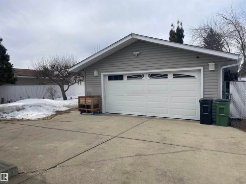 Detached garage with a white sectional door, gray siding, and exterior lighting fixtures - 14212 30 Street, Edmonton, AB - Outdoor With Exterior
