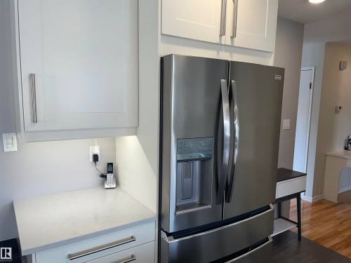 Kitchen featuring white cabinetry with brushed nickel hardware, stainless steel refrigerator with a water and ice dispenser, and light-colored countertops - 14212 30 Street, Edmonton, AB - Indoor Photo Showing Kitchen