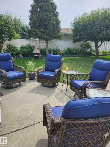 The property features a concrete patio area with a view of the backyard, which includes a lawn and mature trees - 14212 30 Street, Edmonton, AB - Outdoor With Backyard