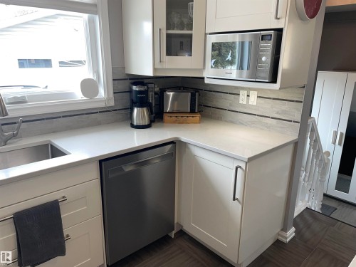 The kitchen features white cabinetry, a stainless steel sink, a built-in microwave, and a dishwasher - 14212 30 Street, Edmonton, AB - Indoor Photo Showing Kitchen