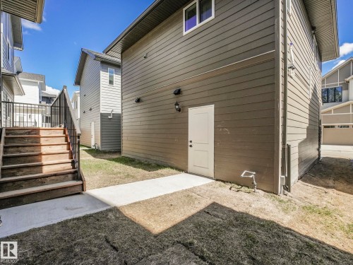 Rear exterior featuring horizontal siding, a white access door, and two outdoor light fixtures - 6125 Crawford Drive, Edmonton, AB - Outdoor With Exterior
