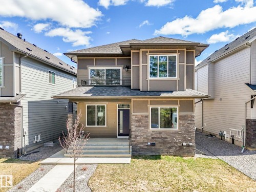 Contemporary two-story residence featuring a multi-tone exterior, dark shingle roof, and stone facade accents - 6125 Crawford Drive, Edmonton, AB - Outdoor