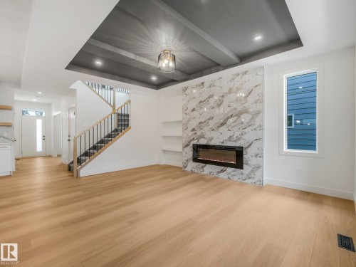 Spacious living area featuring a coffered ceiling, wood-finish flooring, and a fireplace with a stone-finish surround - 6125 Crawford Drive, Edmonton, AB - Indoor Photo Showing Living Room With Fireplace