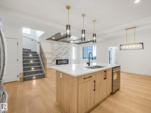 Open-concept interior featuring light wood-finish flooring - 6125 Crawford Drive, Edmonton, AB - Indoor Photo Showing Kitchen With Fireplace With Double Sink