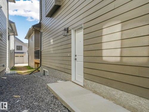 Exterior featuring horizontal siding, a white entry door, and an exterior wall lantern - 6125 Crawford Drive, Edmonton, AB - Outdoor With Exterior
