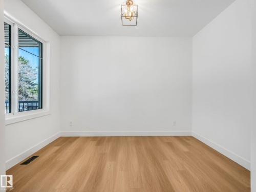 Room featuring wood-finish flooring, white walls, and a modern caged ceiling light fixture - 6125 Crawford Drive, Edmonton, AB - Indoor Photo Showing Other Room