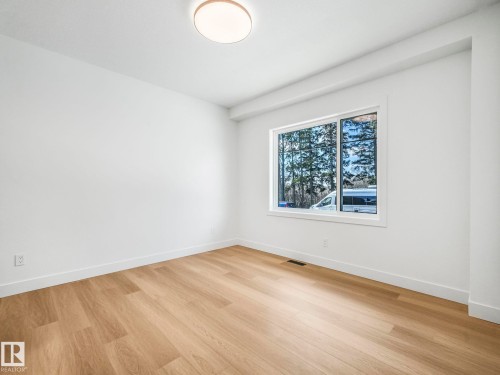 Spacious room featuring wood-finish flooring, white baseboards, and a large window - 6125 Crawford Drive, Edmonton, AB - Indoor Photo Showing Other Room