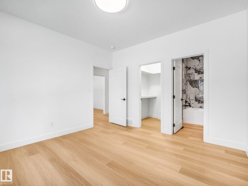 Light wood-finish flooring complements crisp white walls - 6125 Crawford Drive, Edmonton, AB - Indoor Photo Showing Other Room