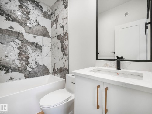 Bathroom featuring a white bathtub, floor-mounted toilet, and large format wall tiles - 6125 Crawford Drive, Edmonton, AB - Indoor Photo Showing Bathroom