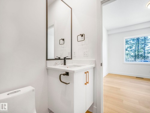 Modern bathroom vanity featuring a rectangular sink, stone countertop, and matte black faucet - 6125 Crawford Drive, Edmonton, AB - Indoor
