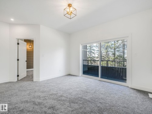 Sliding glass door leading to a balcony with black metal railings - 6125 Crawford Drive, Edmonton, AB - Indoor Photo Showing Other Room