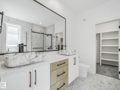Dual marble-finish vessel sinks with wall-mounted matte black faucets and a white countertop - 6125 Crawford Drive, Edmonton, AB - Indoor Photo Showing Bathroom