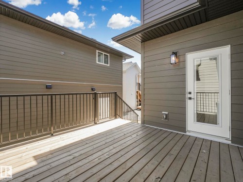 Expansive wood deck with black metal railings, gray horizontal siding, and an exterior light fixture - 6125 Crawford Drive, Edmonton, AB - Outdoor With Deck Patio Veranda With Exterior