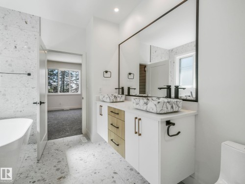 Modern bathroom featuring a dual vanity with white cabinetry, wood-finish drawers, and black hardware - 6125 Crawford Drive, Edmonton, AB - Indoor Photo Showing Bathroom