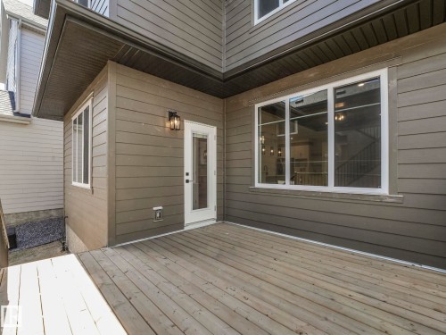 Spacious wooden deck extending from the property, featuring a glass-paned exterior door with an overhead lantern fixture - 6125 Crawford Drive, Edmonton, AB - Outdoor With Exterior