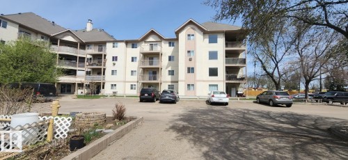 Multi-story residential building featuring light-toned exterior siding, multiple private balconies, and a gabled roofline - 204 11218 80 Street, Edmonton, AB - Outdoor With Balcony With Facade