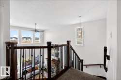 Open concept upper level featuring rich wood-finish railings with black metal balusters - 
