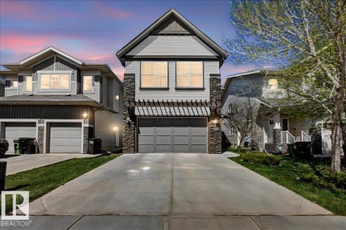 Two-story residence featuring light gray siding with dark gray stone accents, a single-car garage, and a concrete driveway - 3936 Claxton Loop, Edmonton, AB - Outdoor With Facade