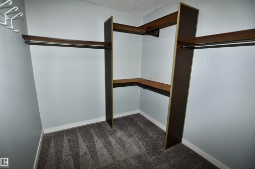 Custom closet system featuring multiple wood-finish shelves and integrated hanging rods - 21 10160 119 Street Nw, Edmonton, AB 