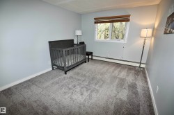 Room featuring light gray walls, gray patterned carpeting, and white baseboards - 