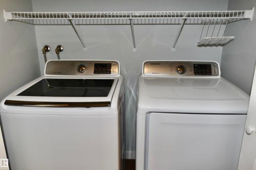 Dedicated insuite laundry area featuring white appliances, a top-load washer, and a front-load dryer - 21 10160 119 Street Nw, Edmonton, AB 