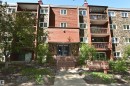 Multi-story residential building featuring a stone and wood-panel exterior, multiple balconies with dark railings, and a prominent entrance with steps - 21 10160 119 Street Nw, Edmonton, AB 