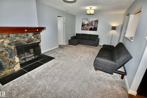 Stone-clad fireplace with a wood mantle and black tile hearth - 21 10160 119 Street Nw, Edmonton, AB 