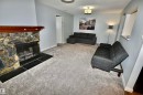Stone-clad fireplace with a wood mantle and black tile hearth - 21 10160 119 Street Nw, Edmonton, AB 