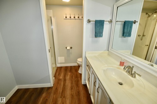 Vanity with integrated sink, wood-finish flooring, and a glass-enclosed shower - 21 10160 119 Street Nw, Edmonton, AB 
