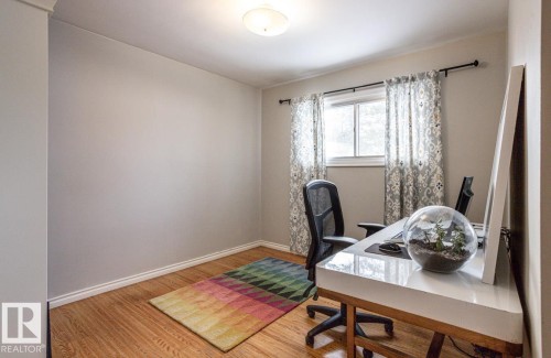 Bright room featuring wood-finish flooring, a double window with black hardware, and light-toned wall paint - 8239 93A Avenue, Edmonton, AB - Indoor Photo Showing Office