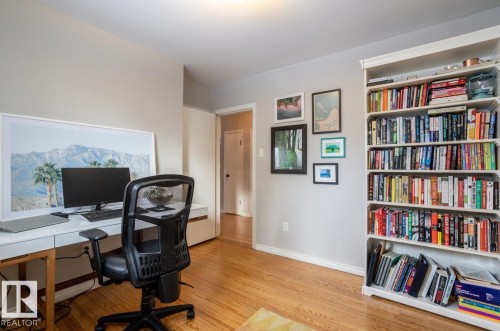 Light-filled room featuring wood-finish flooring, a built-in white bookshelf, and neutral wall paint - 8239 93A Avenue, Edmonton, AB - Indoor Photo Showing Office