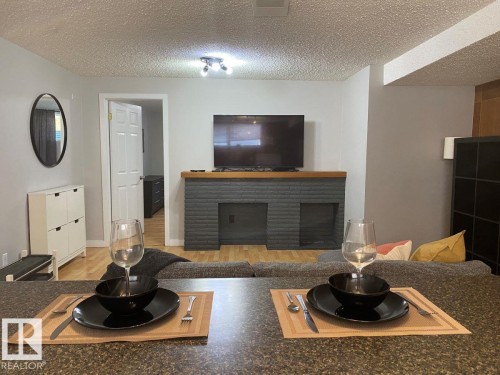 Living area featuring a textured ceiling, recessed lighting, and wood-finish flooring - 8239 93A Avenue, Edmonton, AB - Indoor Photo Showing Living Room With Fireplace