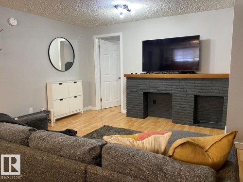 Living space featuring wood-finish flooring and light gray painted walls - 8239 93A Avenue, Edmonton, AB - Indoor Photo Showing Living Room With Fireplace