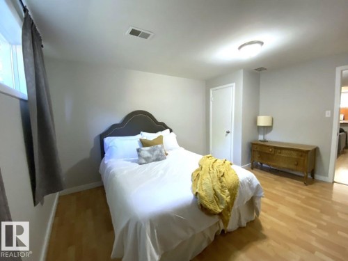 Bedroom featuring wood-finish flooring, a contemporary ceiling light fixture, and a window with drapery rod - 8239 93A Avenue, Edmonton, AB - Indoor Photo Showing Bedroom