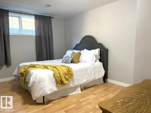 Bedroom featuring light wood-finish flooring, neutral wall tones, and a window with white trim - 8239 93A Avenue, Edmonton, AB - Indoor Photo Showing Bedroom
