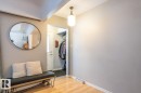 Foyer featuring wood-finish flooring, a wall-mounted light fixture, and an entryway with a white door - 8239 93A Avenue, Edmonton, AB  - Indoor Photo Showing Other Room 