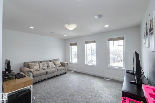 This bright room features three large windows, recessed lighting, and soft carpet flooring - 14 Edgewater Terr North, St. Albert, AB - Indoor Photo Showing Living Room