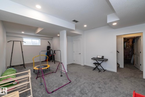 This spacious room features light gray carpeting, recessed lighting, and a white interior door - 14 Edgewater Terr North, St. Albert, AB - Indoor