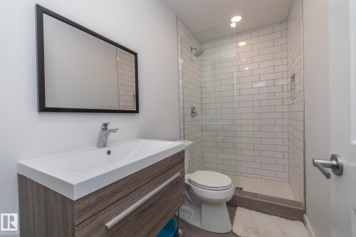 The bathroom features a sleek vanity with a rectangular sink, a framed mirror, and a glass-enclosed shower with subway tile - 14 Edgewater Terr North, St. Albert, AB - Indoor Photo Showing Bathroom
