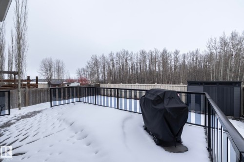 The property features a spacious deck with a black railing, overlooking a fenced yard - 14 Edgewater Terr North, St. Albert, AB - Outdoor