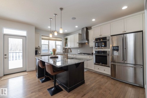 The kitchen features a large island with a stone countertop, pendant lighting, and stainless steel appliances - 14 Edgewater Terr North, St. Albert, AB - Indoor Photo Showing Kitchen With Upgraded Kitchen