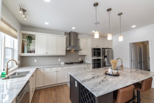 The property features a kitchen with light-colored cabinetry, stainless steel appliances, and a central island with a stone countertop - 14 Edgewater Terr North, St. Albert, AB - Indoor Photo Showing Kitchen With Double Sink With Upgraded Kitchen
