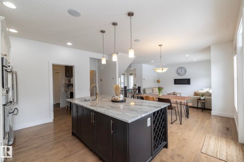 Open concept living area featuring hardwood flooring, recessed lighting, and a kitchen island with a granite countertop, sink, and built-in wine rack - 14 Edgewater Terr North, St. Albert, AB - Indoor Photo Showing Kitchen With Upgraded Kitchen