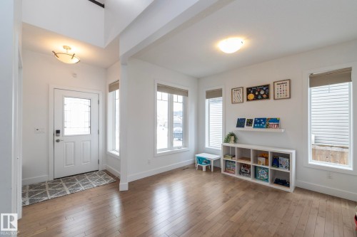 The property features hardwood floors, a white front door with decorative glass, and a neutral color palette throughout - 14 Edgewater Terr North, St. Albert, AB - Indoor Photo Showing Other Room