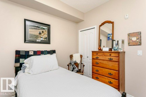 Neutral-toned walls enhance this room, featuring a textured ceiling and a built-in architectural soffit - 323 16807 100 Avenue, Edmonton, AB - Indoor Photo Showing Bedroom
