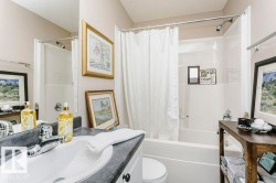 Bathroom featuring a white vanity with a dark countertop and undermount sink, a chrome faucet, and a white tub/shower combination with a chrome showerhead - 