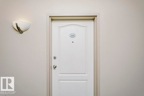 White paneled entry door with polished chrome hardware and an overhead wall sconce - 323 16807 100 Avenue, Edmonton, AB -  Photo Showing Other Room