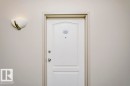 White paneled entry door with polished chrome hardware and an overhead wall sconce - 323 16807 100 Avenue, Edmonton, AB  -  Photo Showing Other Room 