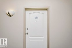White paneled entry door with polished chrome hardware and an overhead wall sconce - 